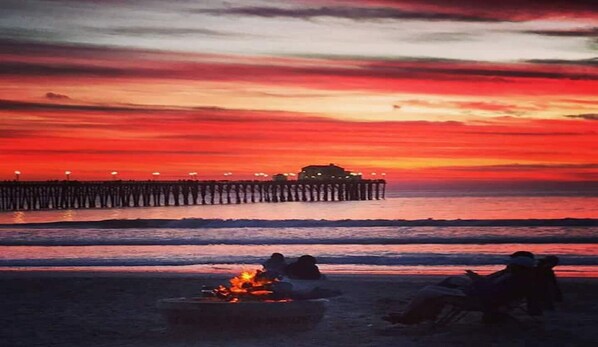 A sunset over the ocean with a pier extending into the water. - Beach Front with Sandy Beaches and Panoramic Ocean View (Oceanside)