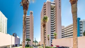 A high-rise building with the name 'PALMS' on its facade, surrounded by palm trees and other buildings.