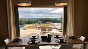 A dining area with a table set for four, overlooking a pool and outdoor seating.