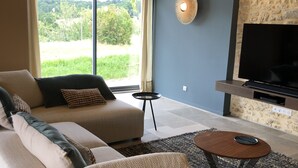 A modern living room with a sofa, a coffee table, a TV, and a stone accent wall.