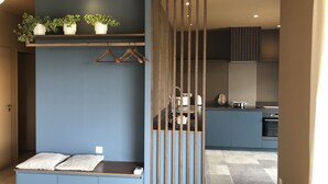A modern kitchen with a blue color scheme, wooden hanging racks, and potted plants on a shelf.