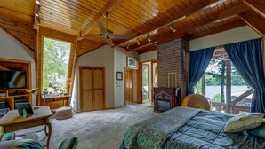 Ein geräumiges Schlafzimmer mit einem großen Bett, einem Schreibtisch mit Laptop, einem Fernseher und einem Kamin.