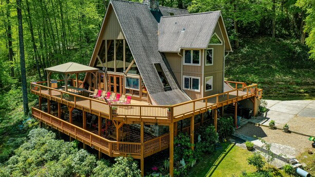 Eine zweigeschossige Holzhütte mit einer Terrasse, umgeben von dichtem Wald.