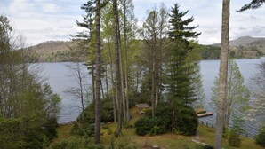 Eine Seehütte mit Steg, umgeben von dichtem Wald und freiem Blick auf den See.