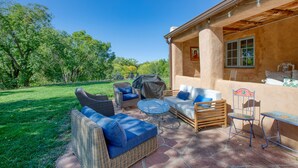 An outdoor patio with wicker furniture, a glass table, and a covered grill area.