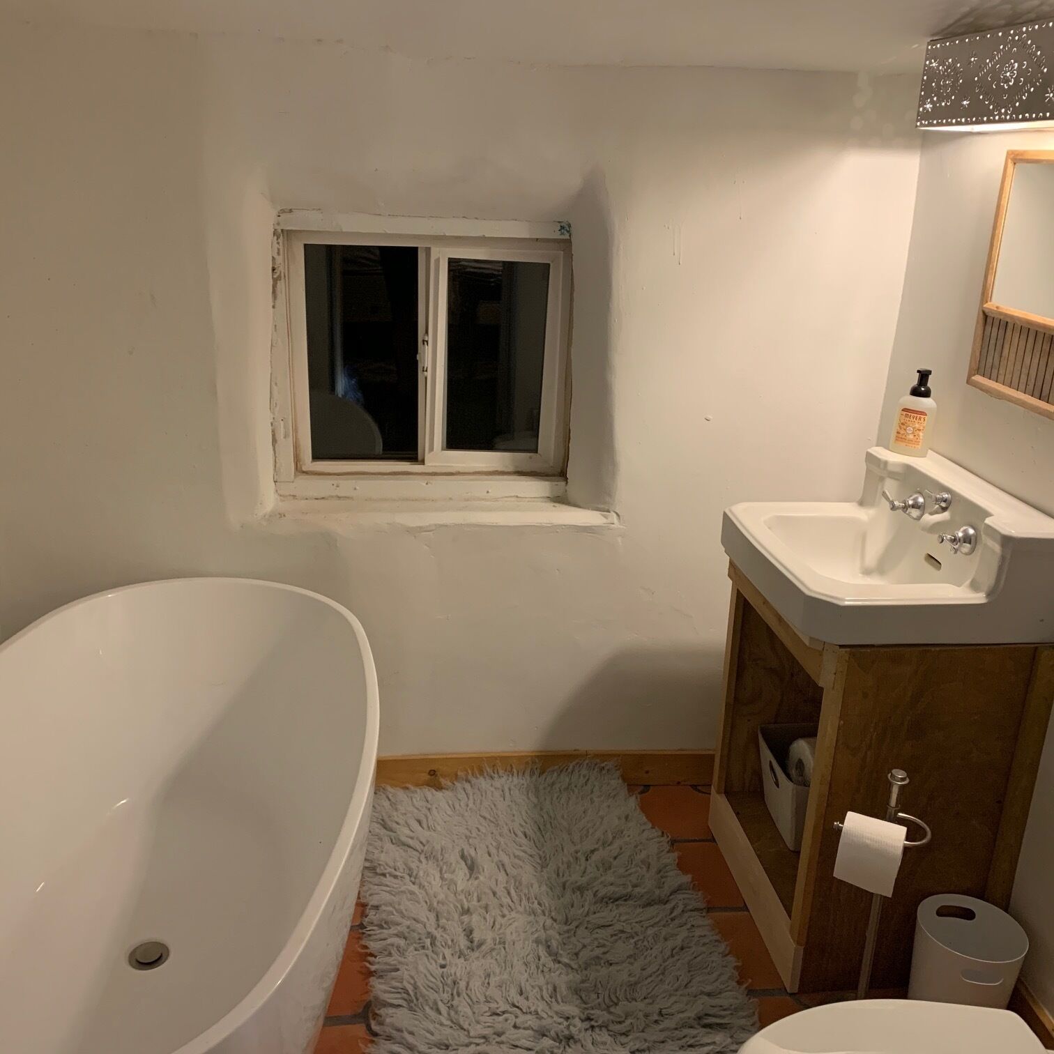 Un baño con bañera, lavamanos, ventana e inodoro.
