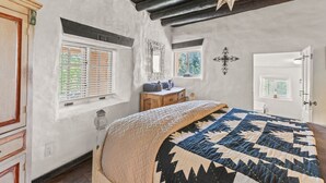 A bedroom with a large bed, a dresser, a vanity, and a door with a window.