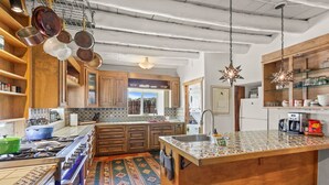 A kitchen with wooden cabinets, a tiled backsplash, a stove, and hanging star-shaped lights.