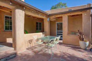 A patio with a table and chairs, a potted plant, and a door. - Taos Hacienda Del Sol (Ranchos de Taos)
