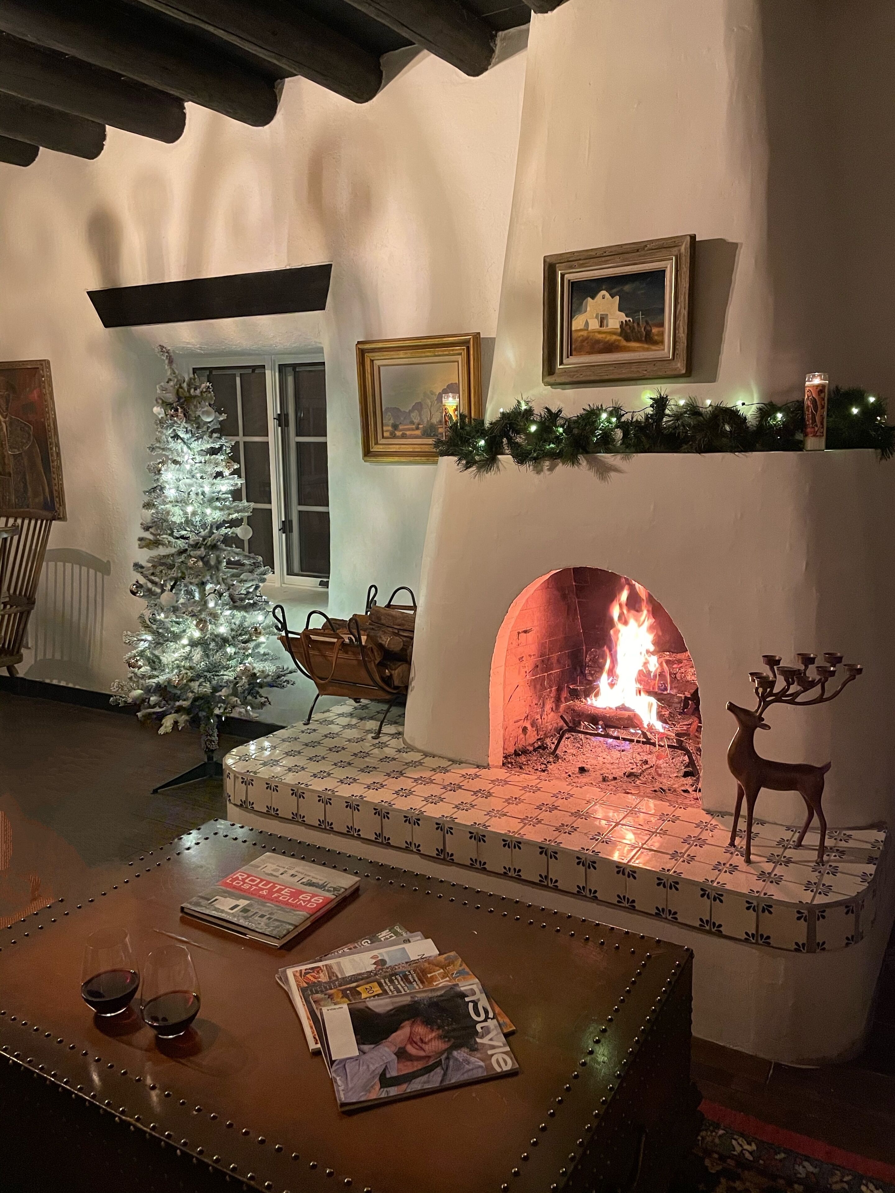 Ein gemütliches Wohnzimmer mit Kamin, einem geschmückten Weihnachtsbaum und einem Kaminbrett mit gerahmten Bildern.