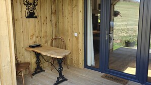Un intérieur en bois avec une table et des chaises, une décoration représentant une tête de taureau et une porte-fenêtre coulissante donnant sur l’extérieur.
