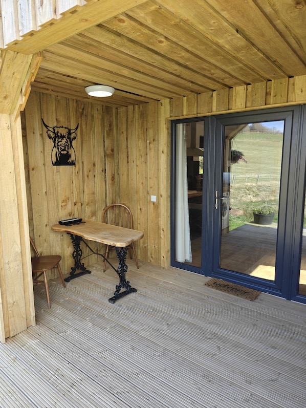 Ein rustikaler Innenraum mit Tisch und Stühlen, einer Stierkopf-Dekoration und einer Glastür zum Garten.