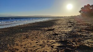 Une plage avec des vagues, un ciel dégagé et le soleil se couchant ou se levant.