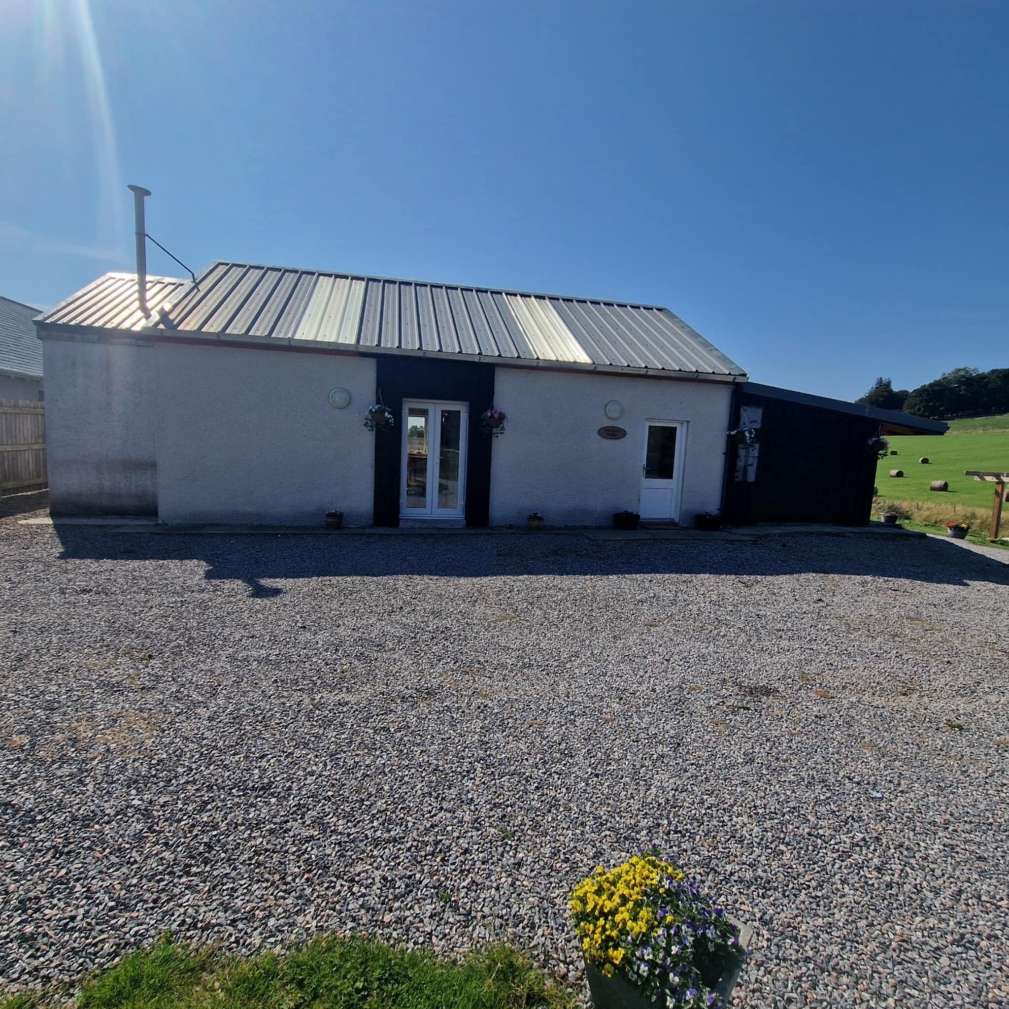 Un bâtiment avec une allée en gravier et un toit en métal.