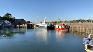 Un port où deux bateaux sont amarrés à un quai, entouré de bâtiments et sous un ciel dégagé.