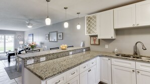 Een moderne keuken met granieten aanrechtbladen, witte kastjes en hanglampen.