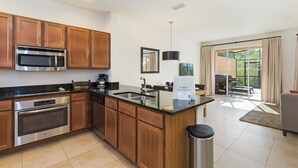 A modern kitchen with wooden cabinets, stainless steel appliances, and a large island with a sink.