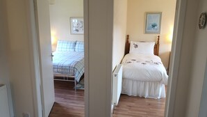 A bedroom with a wooden bed, a bedside table, and a framed picture on the wall. - Newholme Self-catering Bungalow (Pitlochry)