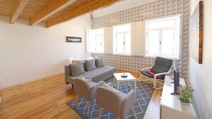 Un salon moderne avec un plafond en bois, un canapé gris, une table blanche et une chaise noire.
