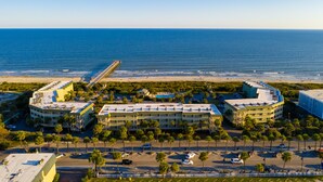 A coastal hotel with multiple buildings, a pier, and a beach in the background.