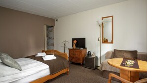 Habitación de hotel con dos camas, un televisor, un aparador, una cafetera y una mesita con mantel individual.