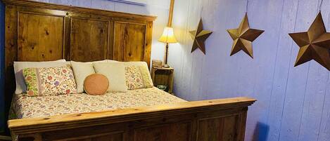 A bed with a wooden headboard, a bench, and star decorations on the wall.