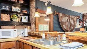 Une cuisine avec des meubles de rangement en bois, un évier en acier inoxydable, un four à micro-ondes et un plan de travail en bois.