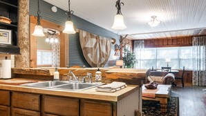 Une cuisine rustique avec des meubles en bois, un grand îlot central doté d’un évier et des luminaires suspendus.