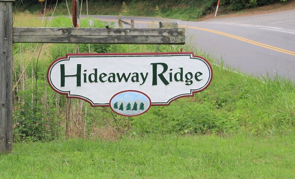 A sign for Hideaway Ridge with a simple, rustic design and a depiction of trees.