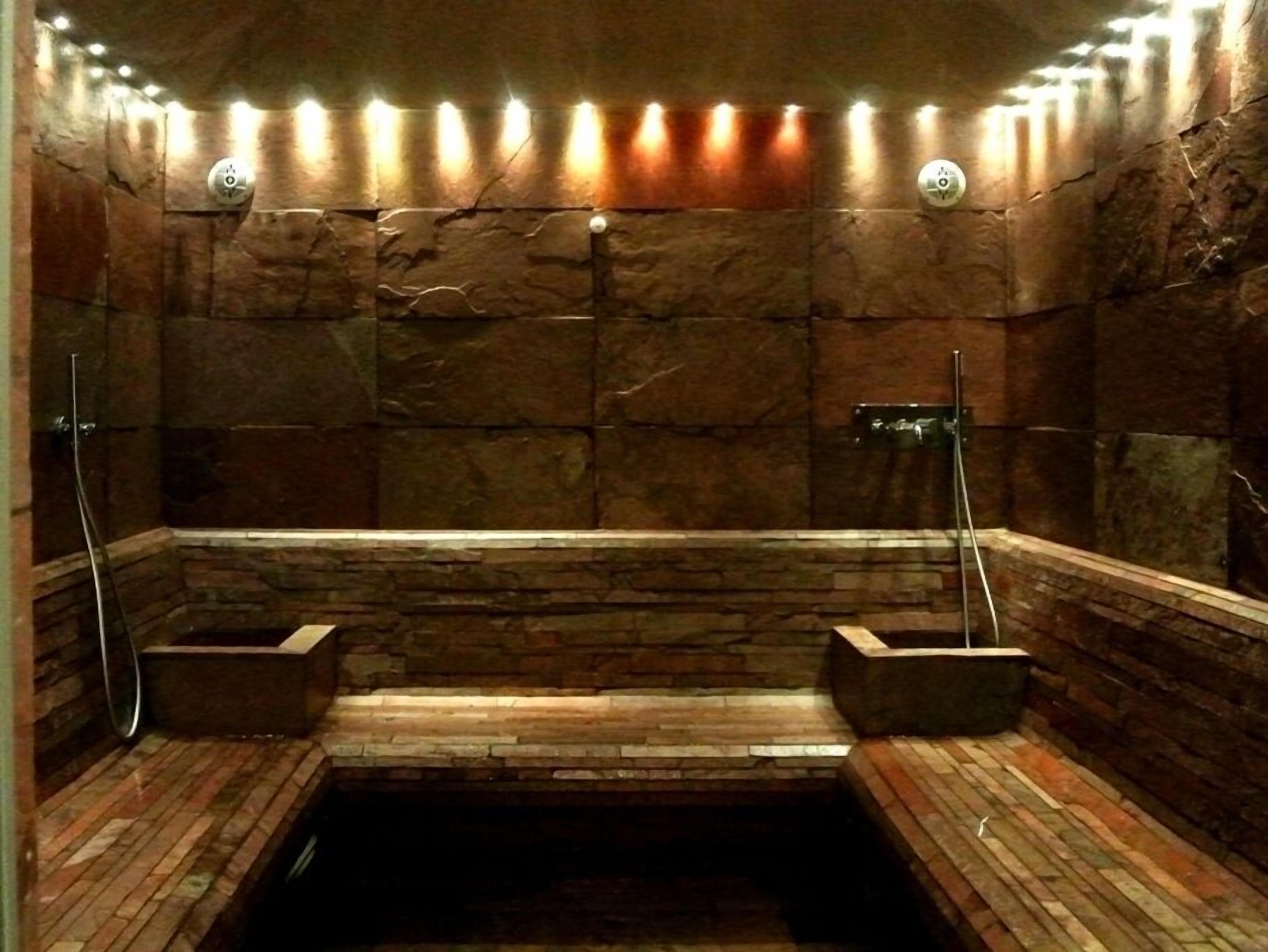 A stone-walled sauna with a wooden bench and two benches on either side.
