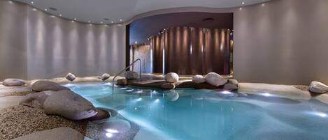 A spa area with a hot tub, surrounded by rocks and a wooden deck.