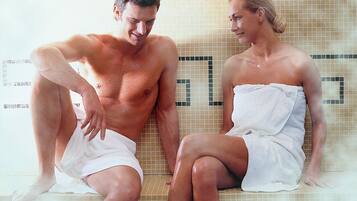 Dos personas sentadas en un banco de baldosas en un ambiente de spa.
