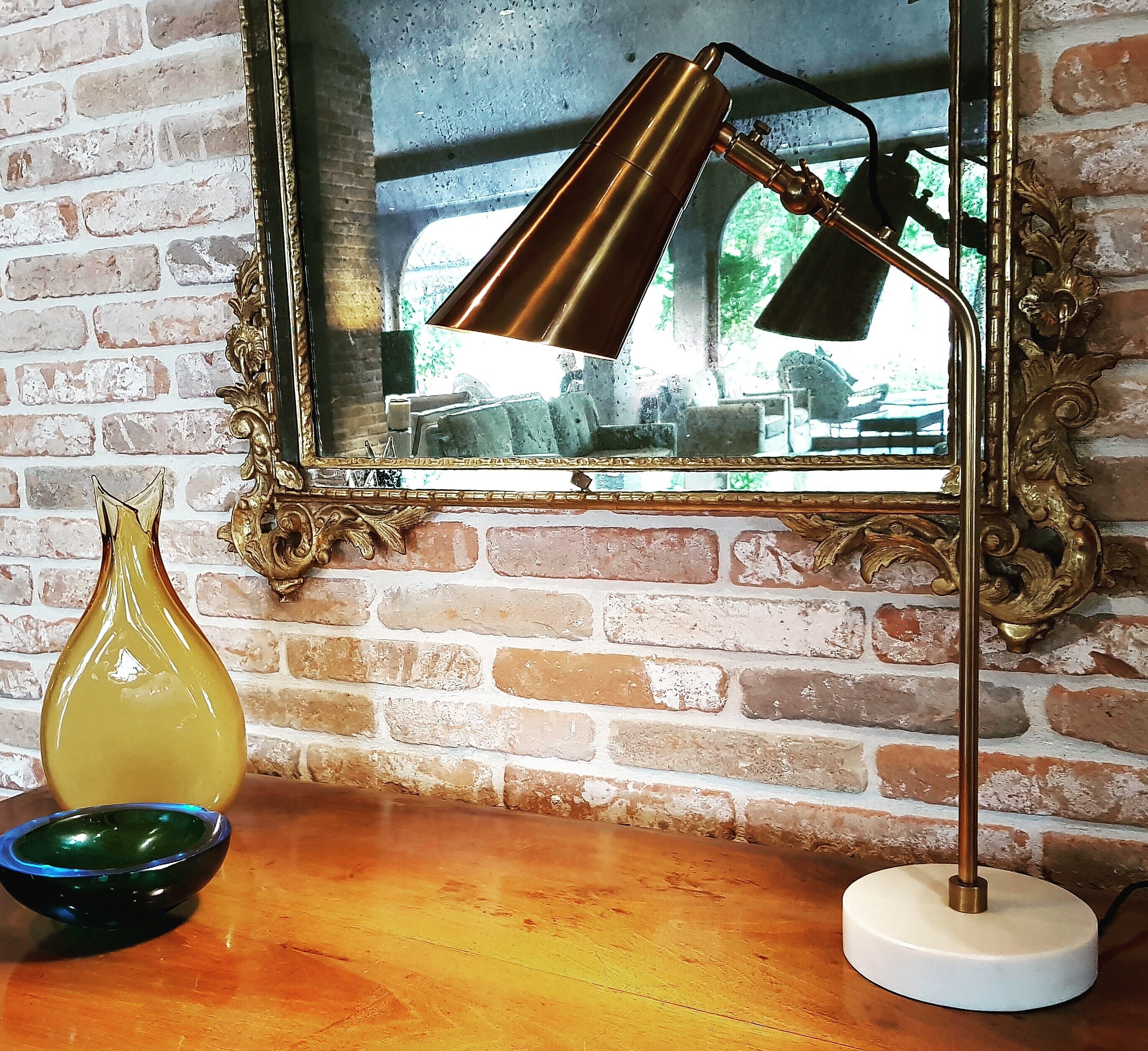 A desk lamp with a metallic finish, a decorative vase, and a bowl on a wooden surface.