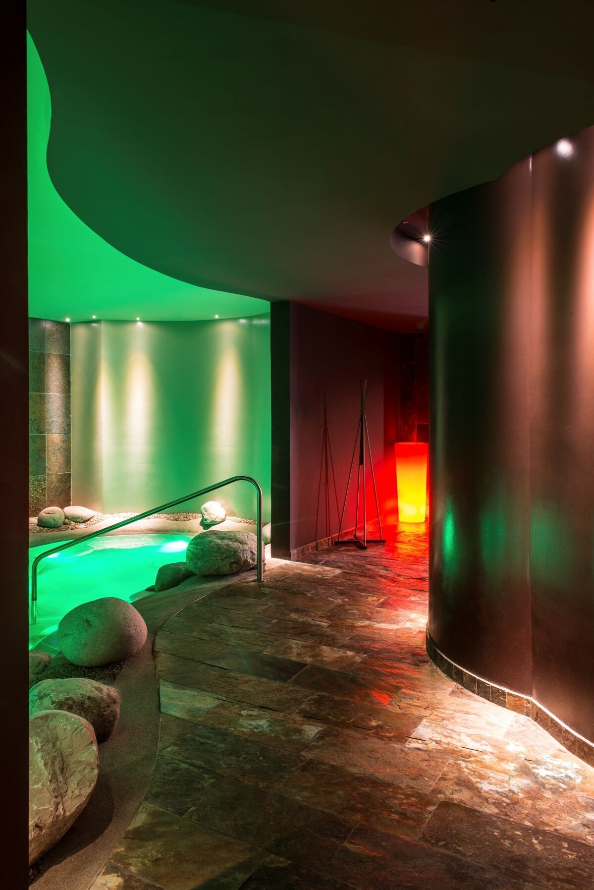 A spa area with a hot tub, stone seating, and a wooden floor.