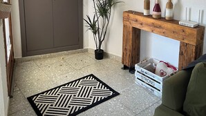 Et værelse med en stor garderobe, et træsofabord med dekorative flasker, et spejl og en potteplante.
