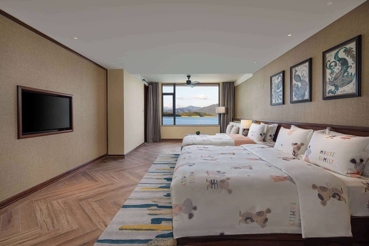 Ein Hotelzimmer mit einem großen Bett, einem Flachbildfernseher und Blick auf die Berge.