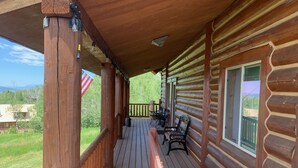 Una baita di legno con veranda, posti a sedere all'aperto e vista sul paesaggio circostante.