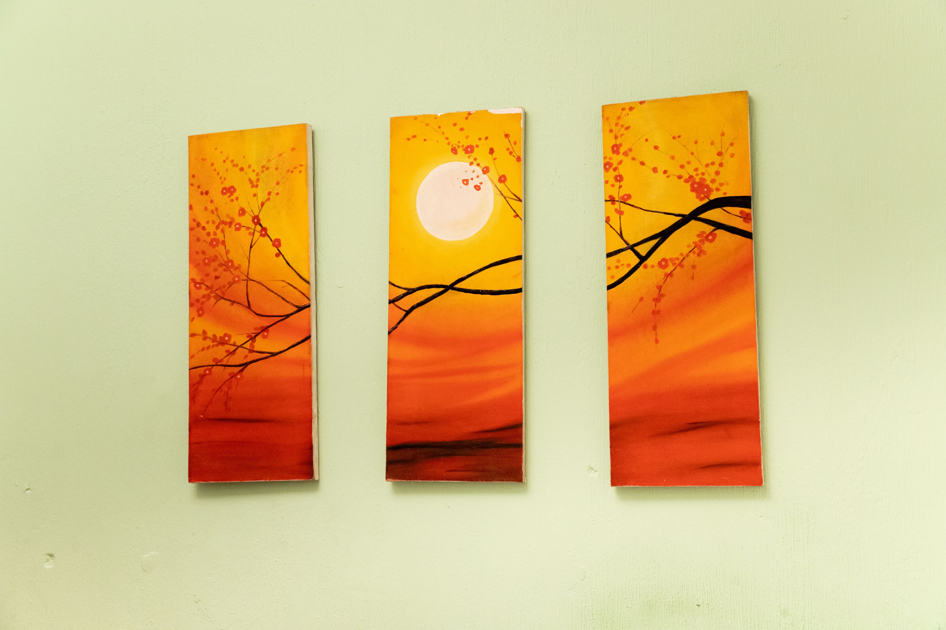 Three vertical panels with a sunset and moon theme, displayed on a plain wall.
