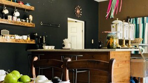 Una cocina con estantes de madera, una mesa de comedor con vajilla blanca y una cesta de frutas.