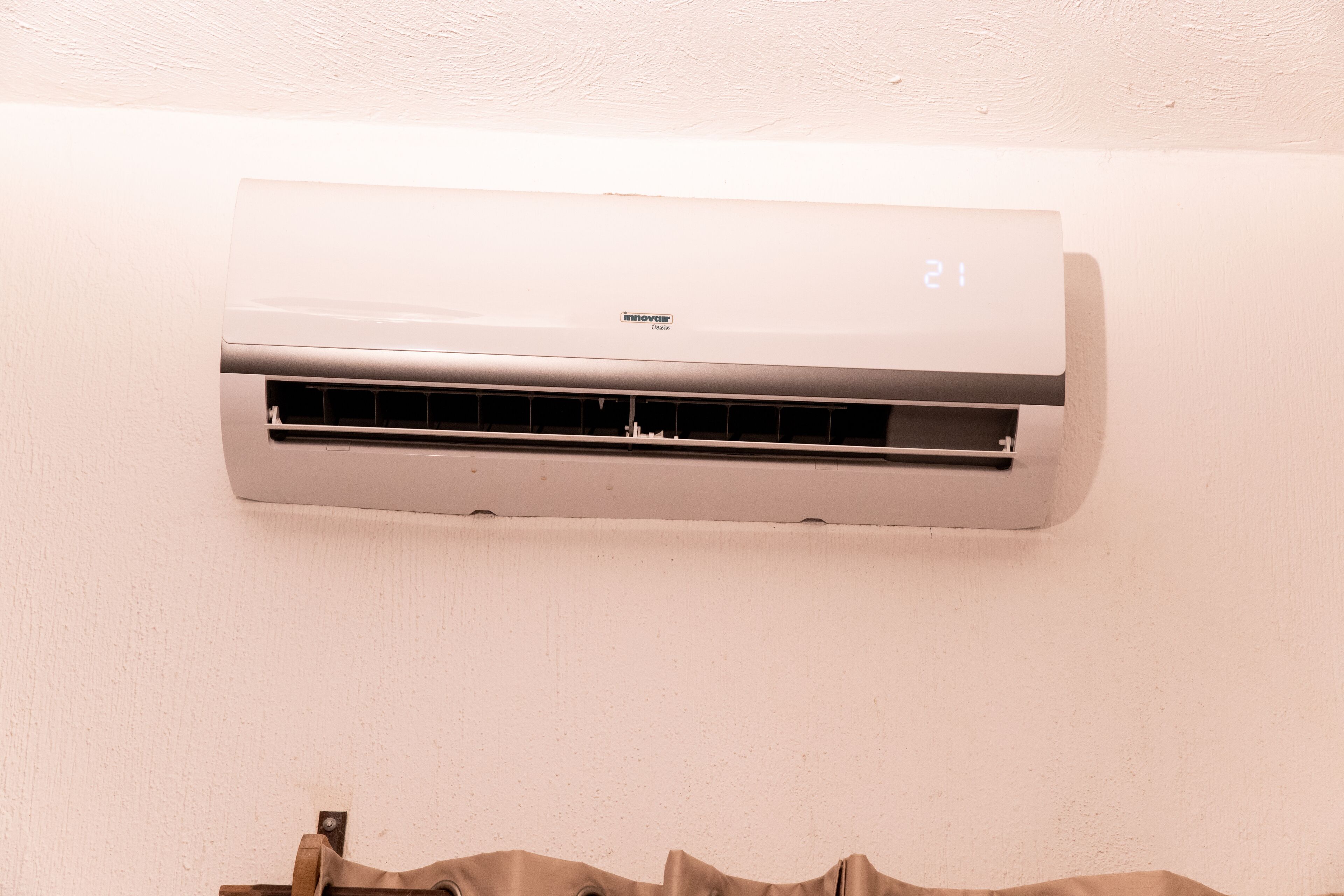 A white air conditioning unit mounted on a wall with a digital display showing the temperature.