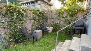 A backyard with a wooden fence, a concrete staircase, and outdoor furniture including two chairs and a table.