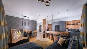 Una sala de estar moderna con un sofá azul oscuro, una mesa de centro de madera y un comedor con sillas y una mesa.