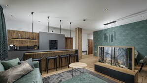 A modern living room with a green sofa, a coffee table, and a large aquarium. - Wohnung 3 in Luxury Apartments "R6 Tegernsee" (Bad Wiessee)