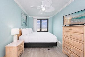A bedroom with a bed, a nightstand, a dresser, a ceiling fan, and a TV.