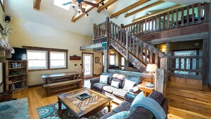 A spacious living room with a wooden staircase, a sofa set, a coffee table, and a bookshelf. - Rest and rejuvenate in seclusion at Nature's Nest! (Nashville)