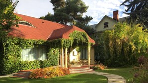 A house with a red roof, ivy-covered walls, a front porch with a bench, and a garden with a curved pathway.