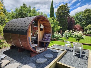 A cylindrical wooden pod with a sloped roof, a small porch, and a seating area with a bench and a chair. - The Fern & Thistle Boutique Accommodation - Drinks, Hotpool, Sauna (Benhar)