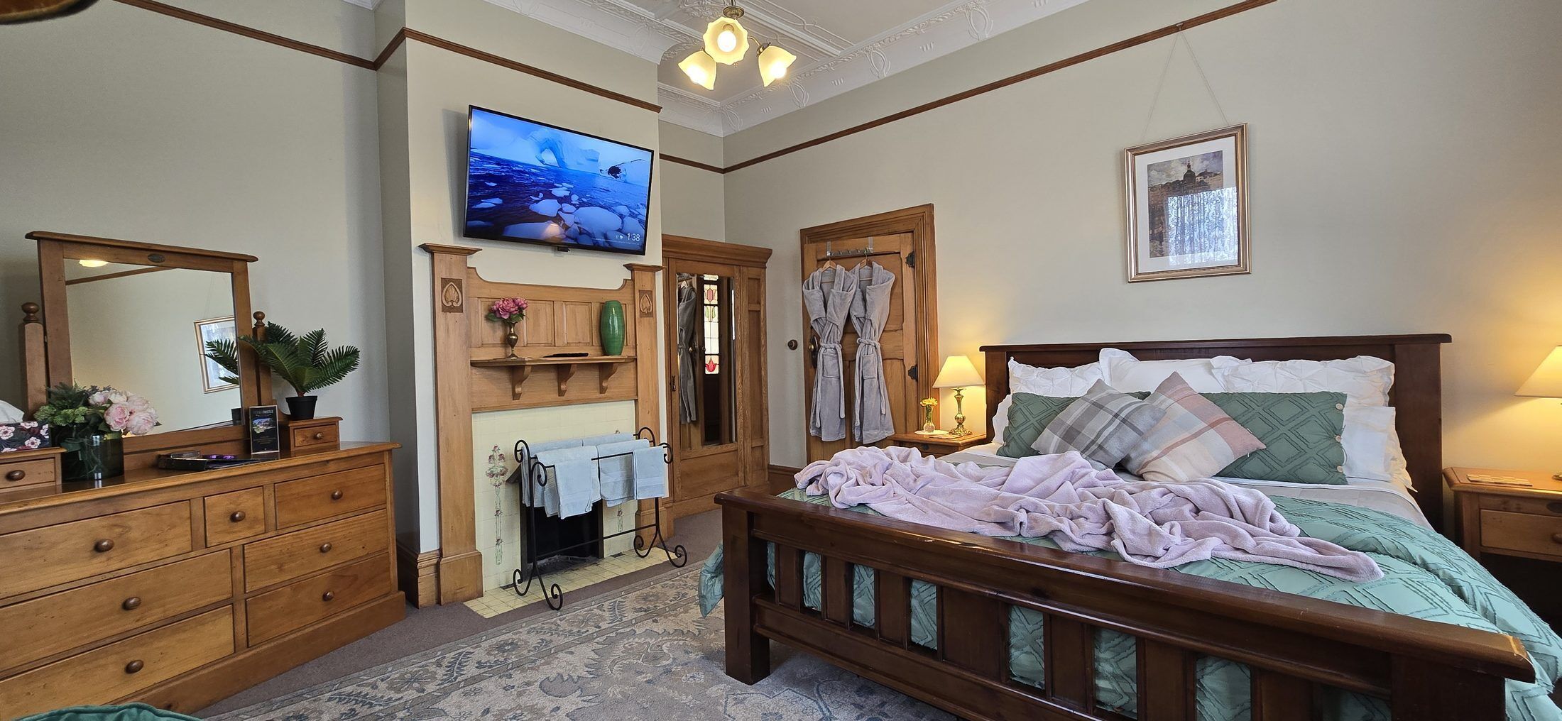 Ein Schlafzimmer mit einem Holzbett, einem Fernseher über einem Kamin und einem gerahmten Bild an der Wand.