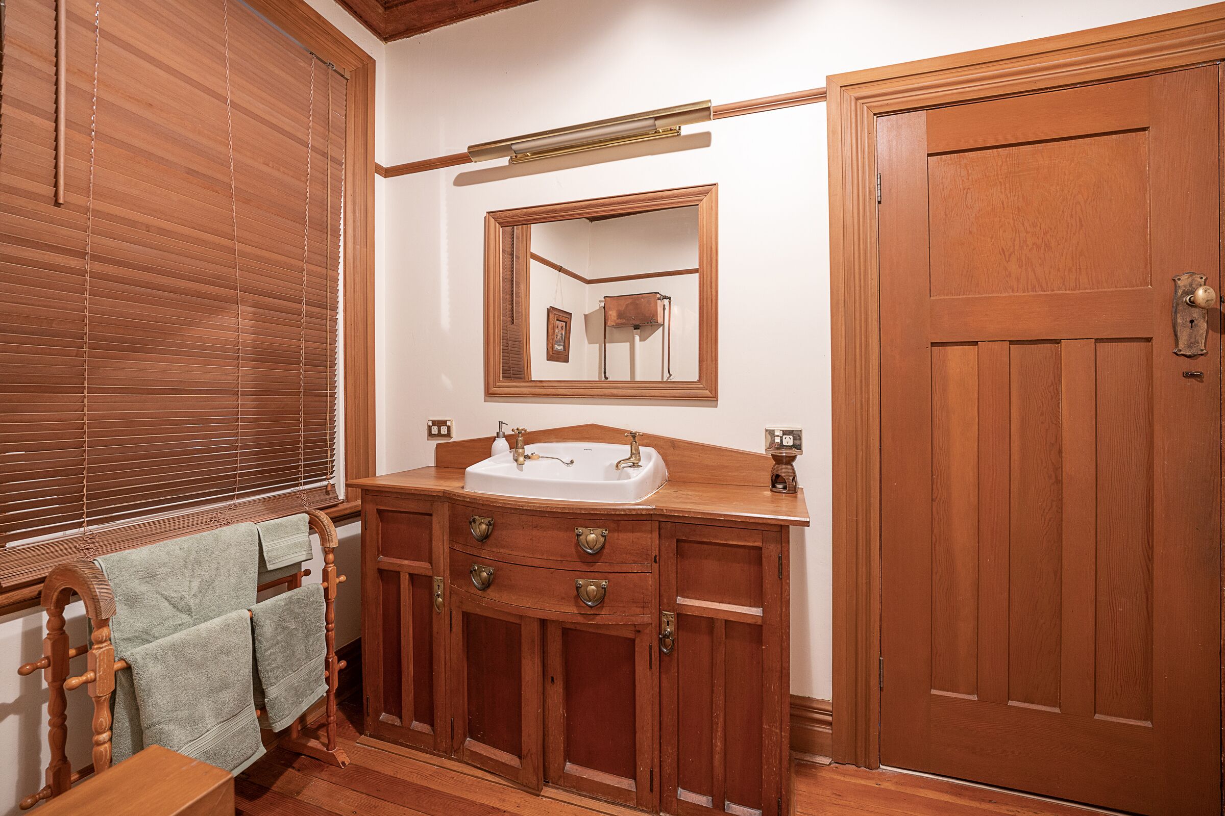 Un baño de madera con lavabo, espejo y puerta.