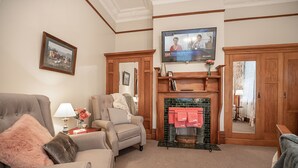 A living room with a fireplace, a television mounted above it, and a framed picture on the wall. - The Fern & Thistle Boutique Accommodation - Drinks, Hotpool, Sauna (Benhar)
